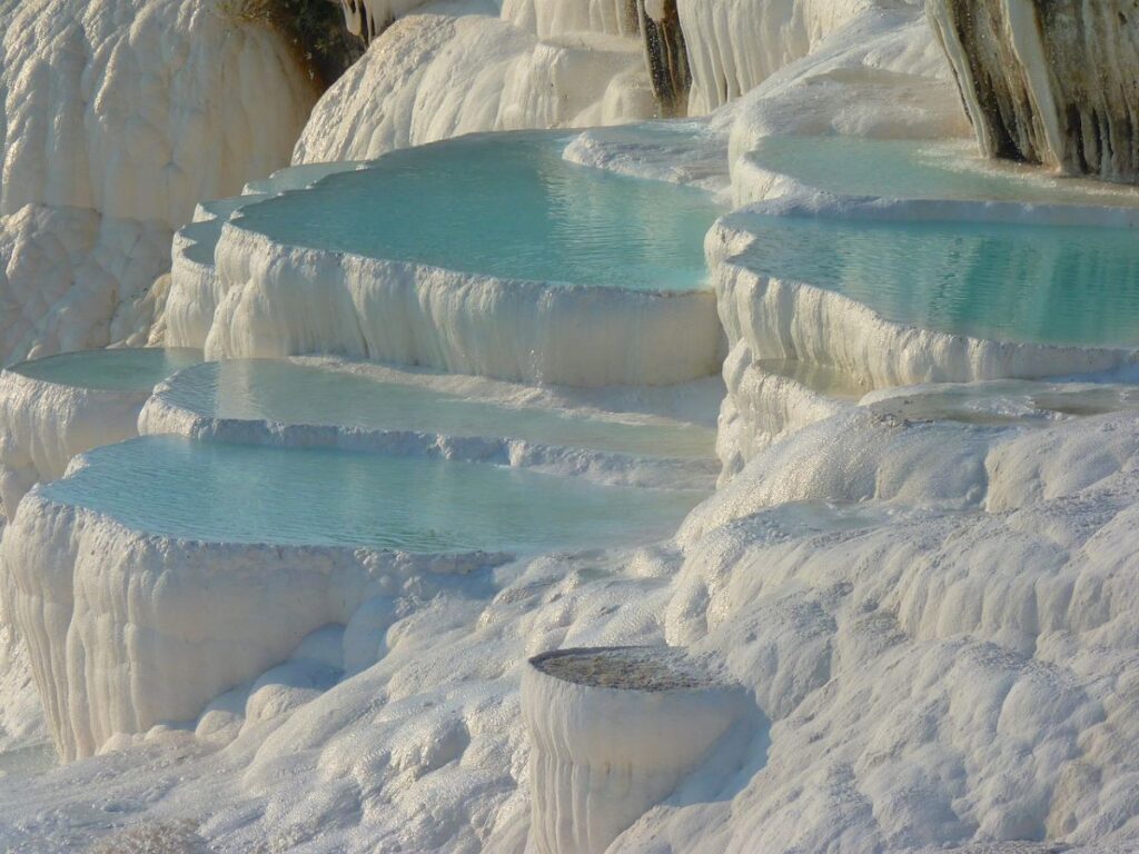 Pamukkale, a natural wonder in Turkey, shows stunning white travertine terraces with warm, mineral-rich waters.