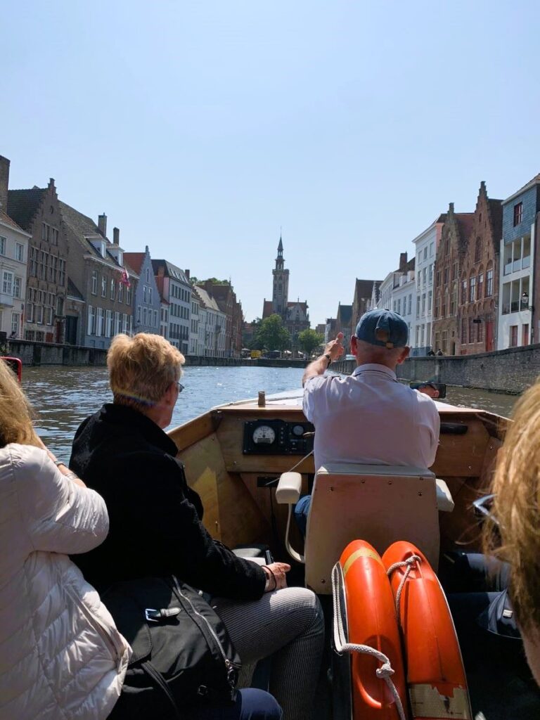 Day trip to Bruges from Brussels - Spiegelrei canal boat ride with the view of the tower of Poortersloge